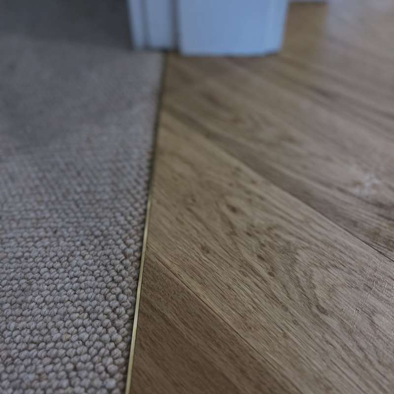 Carpet meeting a timber floor at a brass transition strip