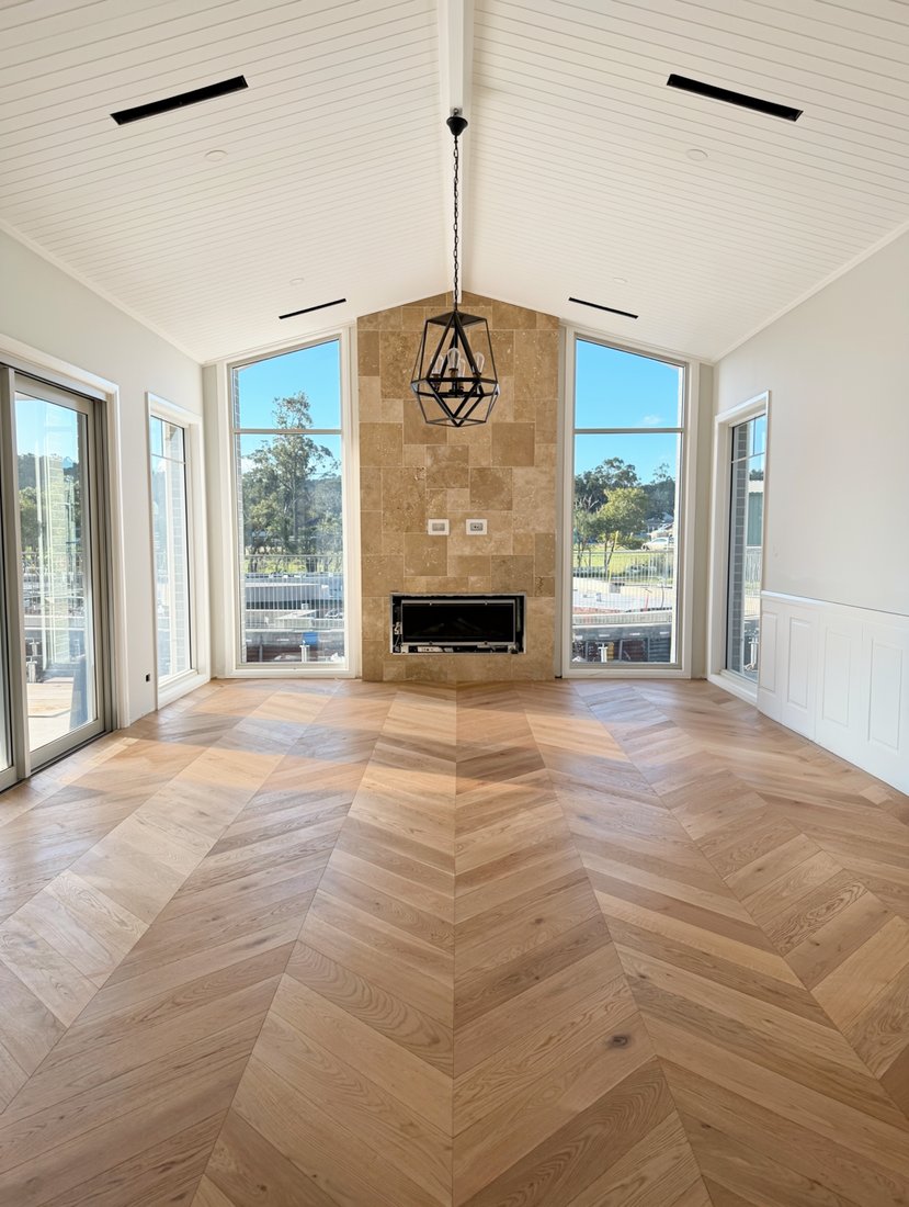 Engineered timber chevron flooring in a vaulted living room with a stone fireplace