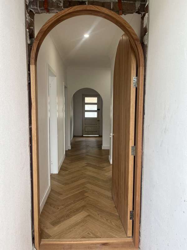 Hybrid herringbone flooring running down an arched hallway