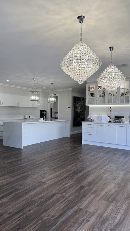 Dark vinyl plank flooring through a white open-plan kitchen